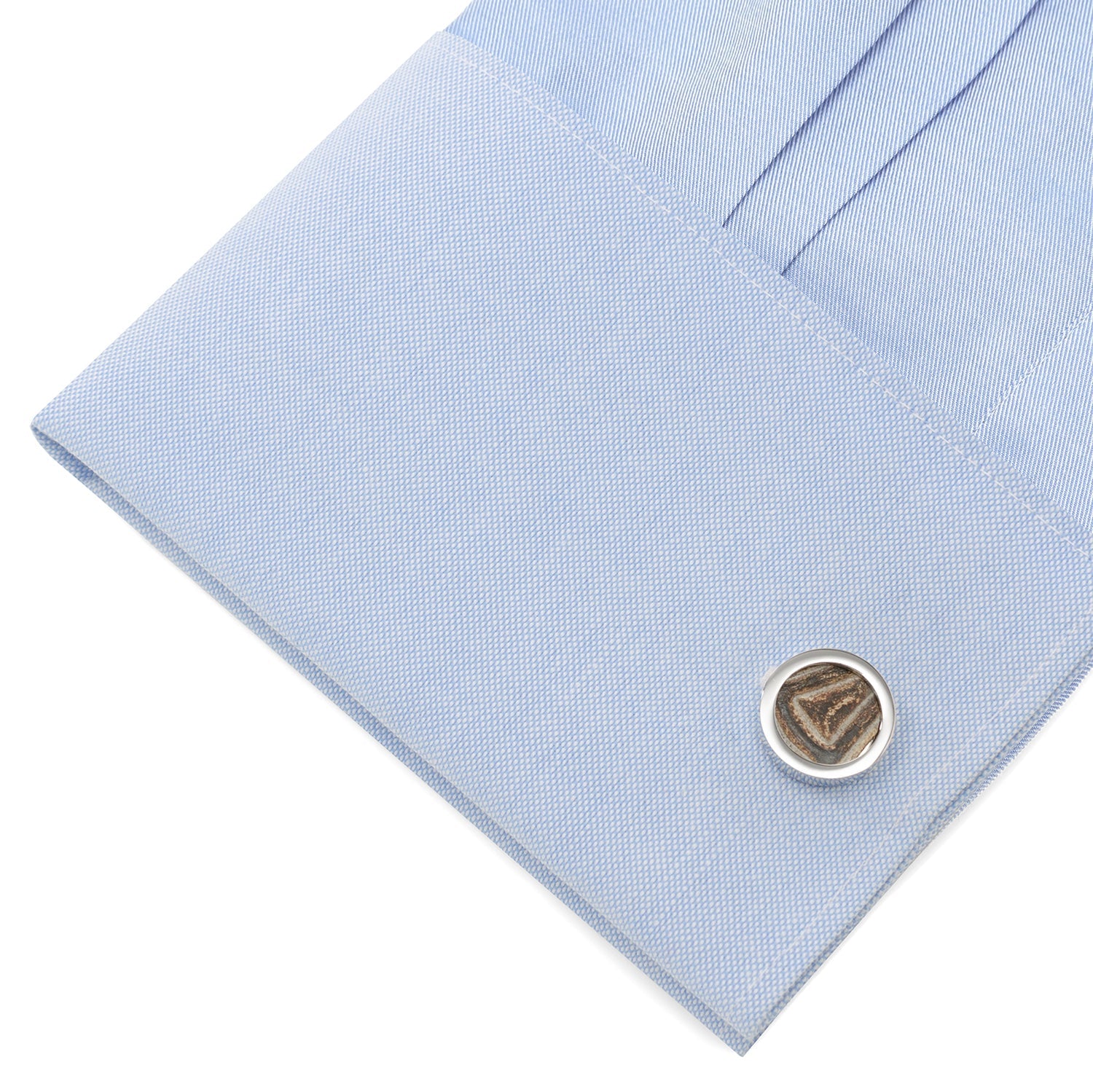 Close-up of a light blue shirt cuff with a cufflink on a white background