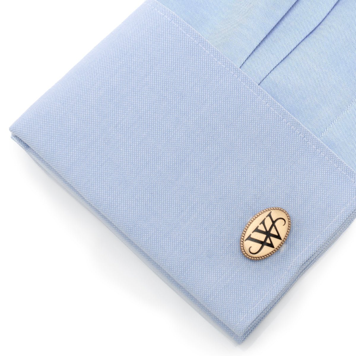 Cufflink on a light blue dress shirt with a white background