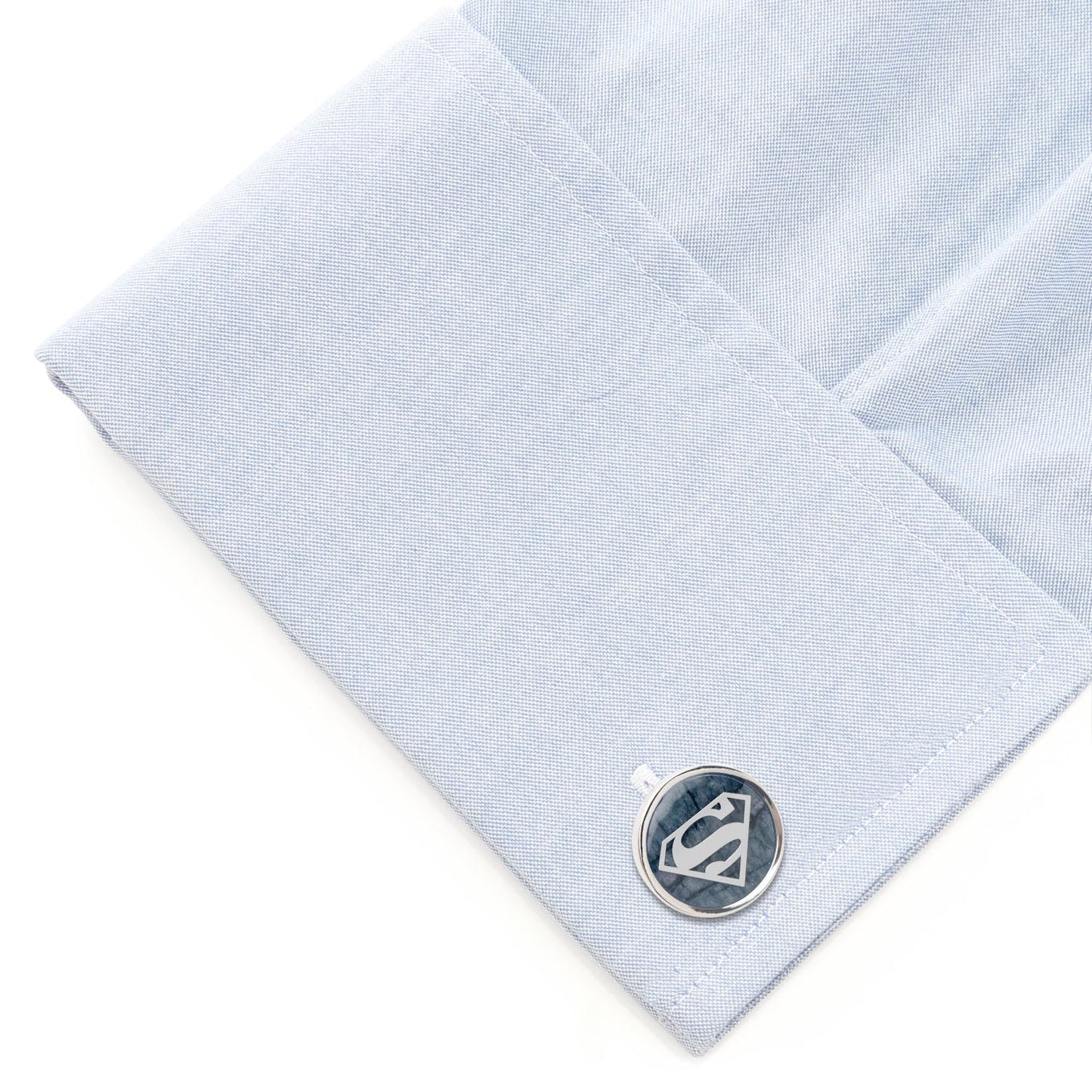 Cufflink on a light blue dress shirt with a white background