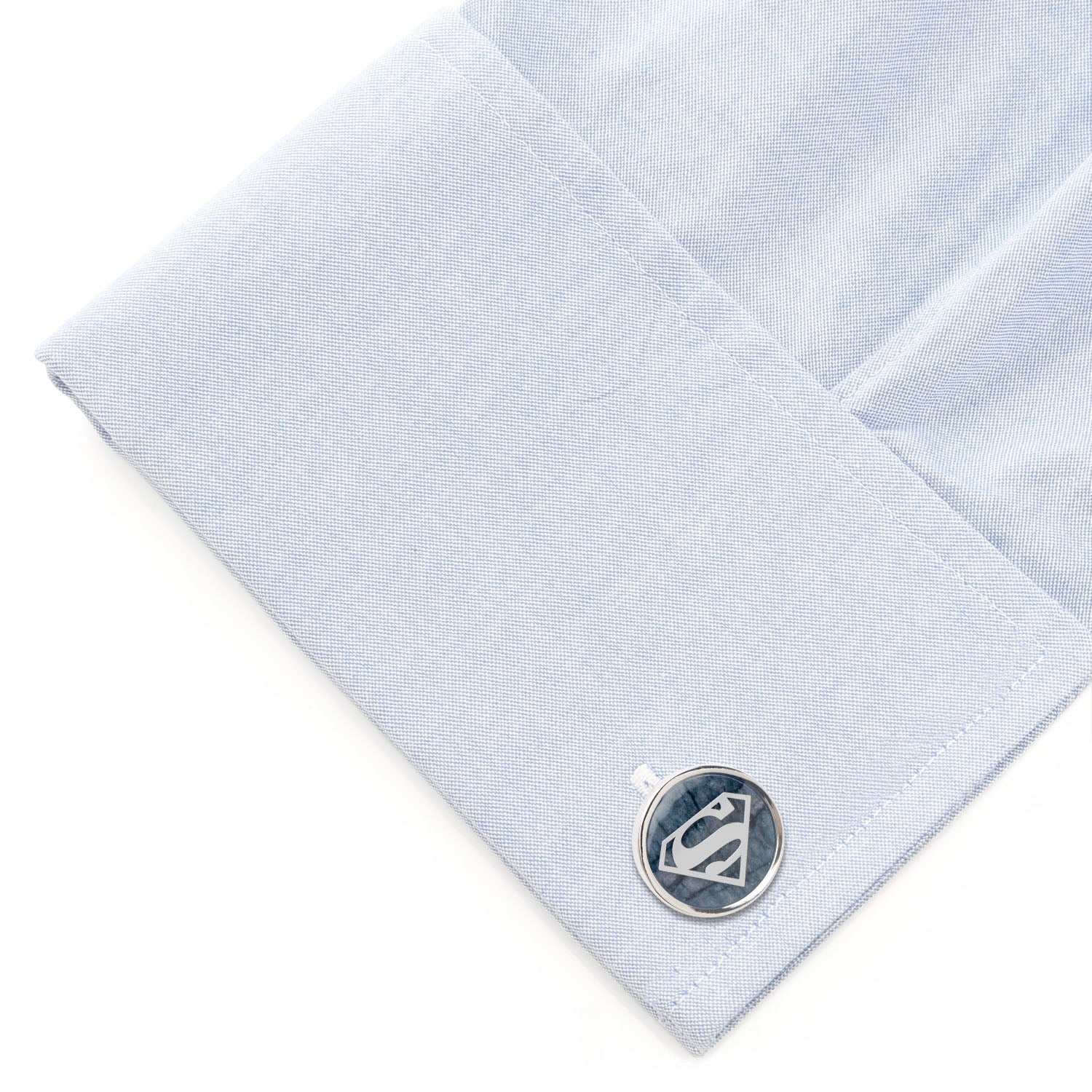 Cufflink on a light blue dress shirt with a white background