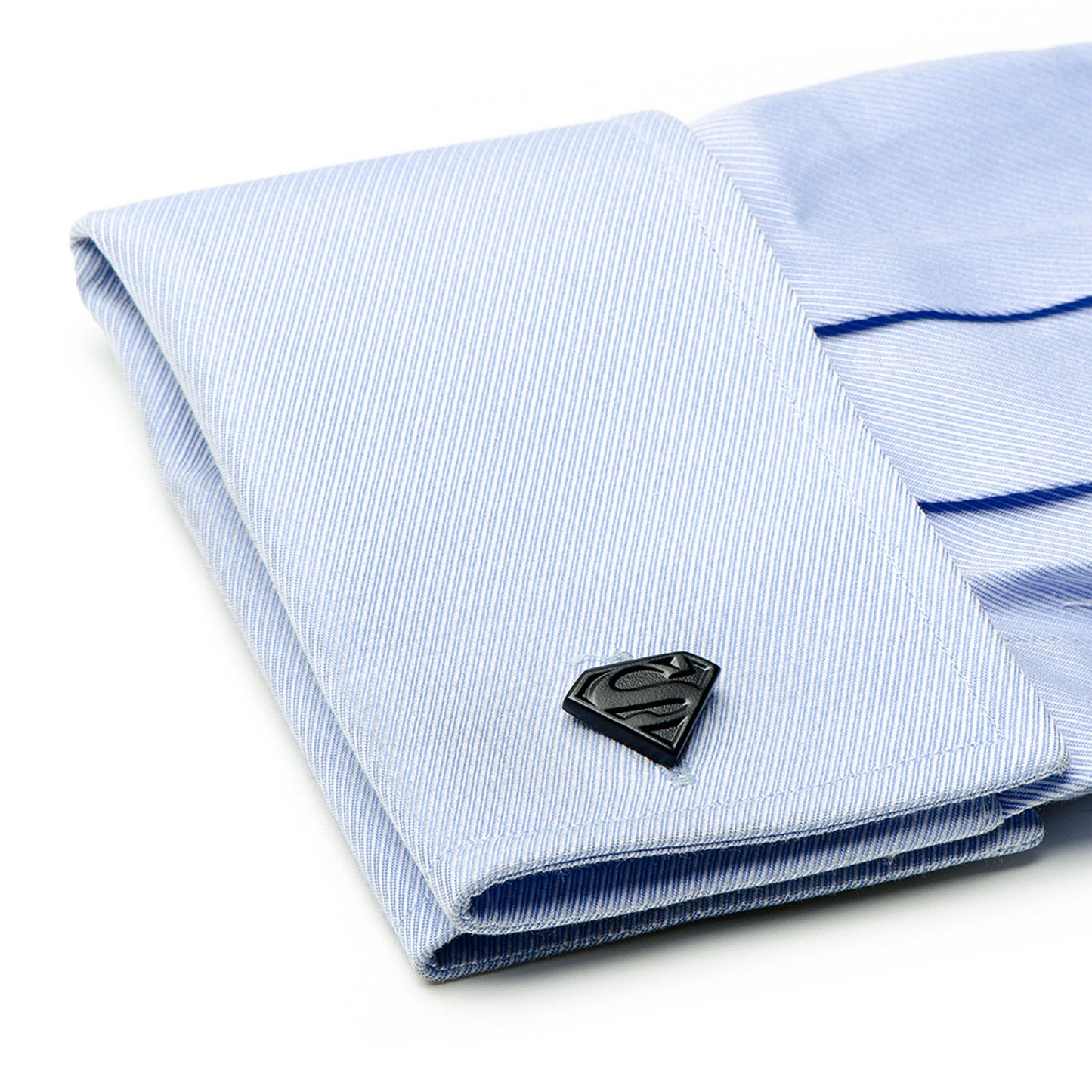 Folded light blue shirt with Superman logo cufflink on a white background