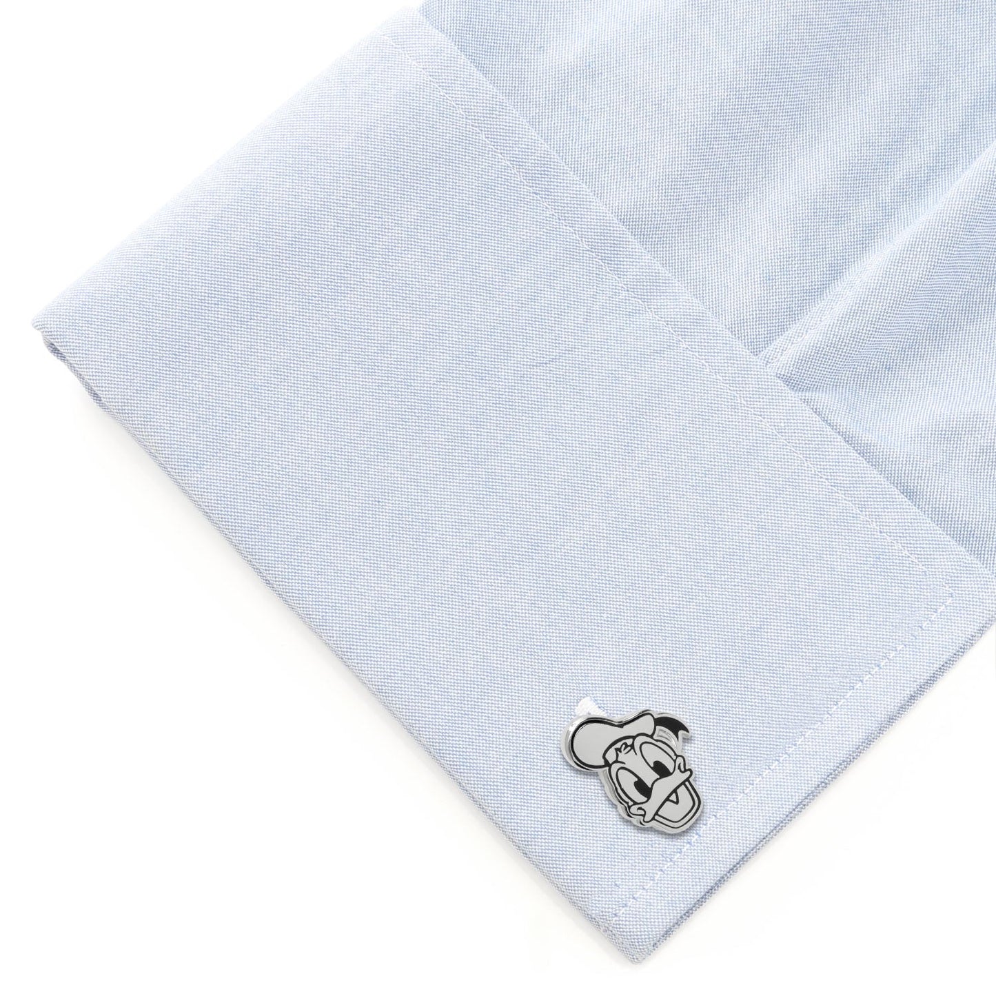 Cufflink on a light blue dress shirt with a white background