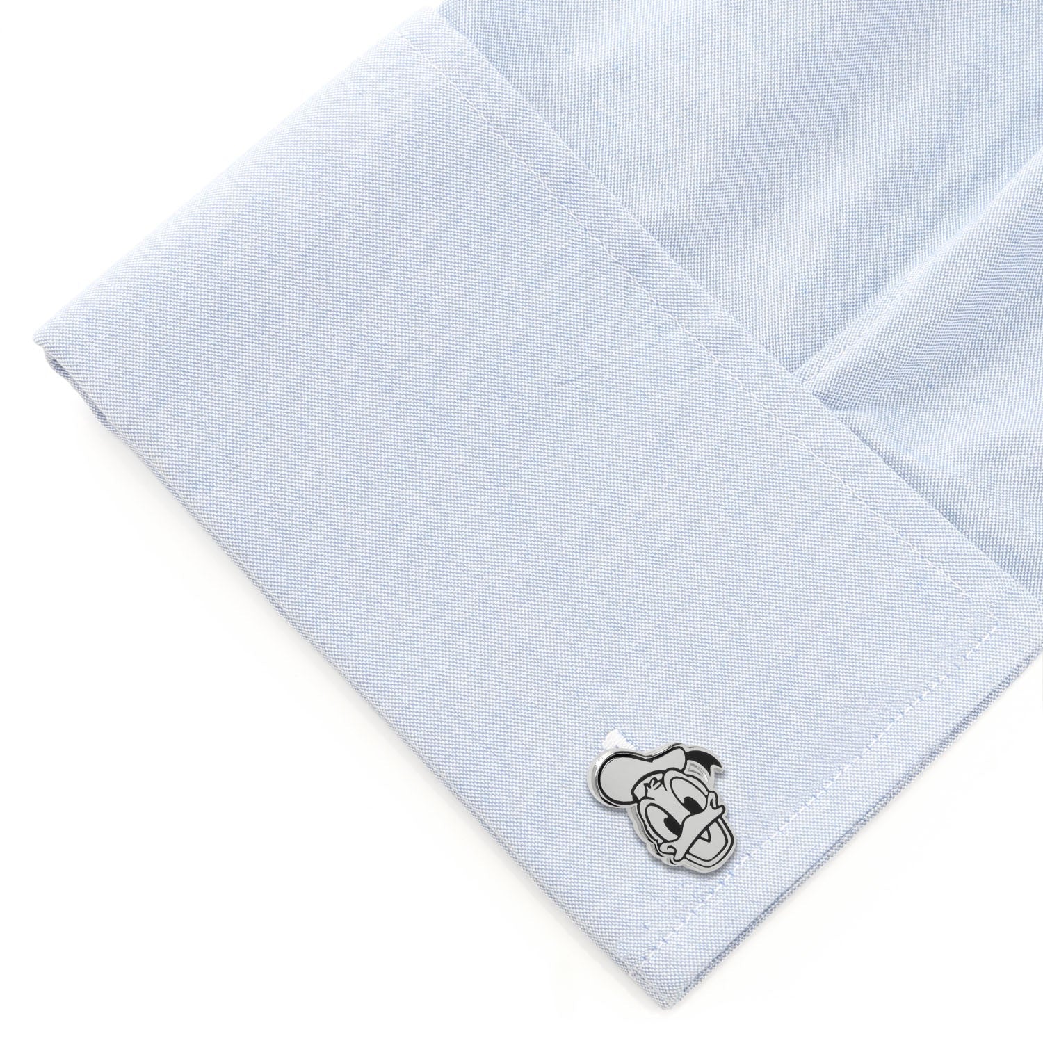Cufflink on a light blue dress shirt with a white background