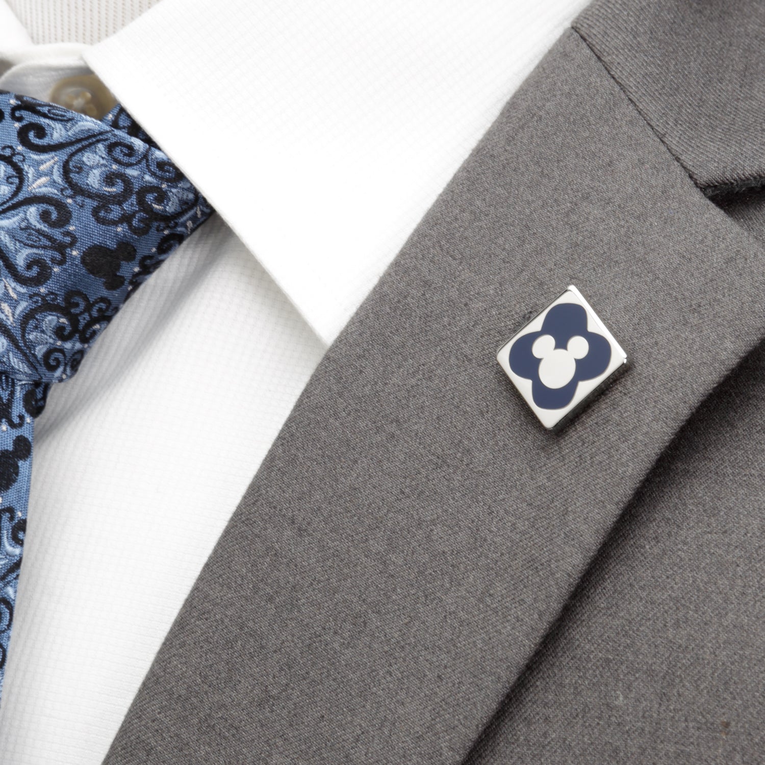 Gray suit jacket with a decorative pin and patterned tie on a white background