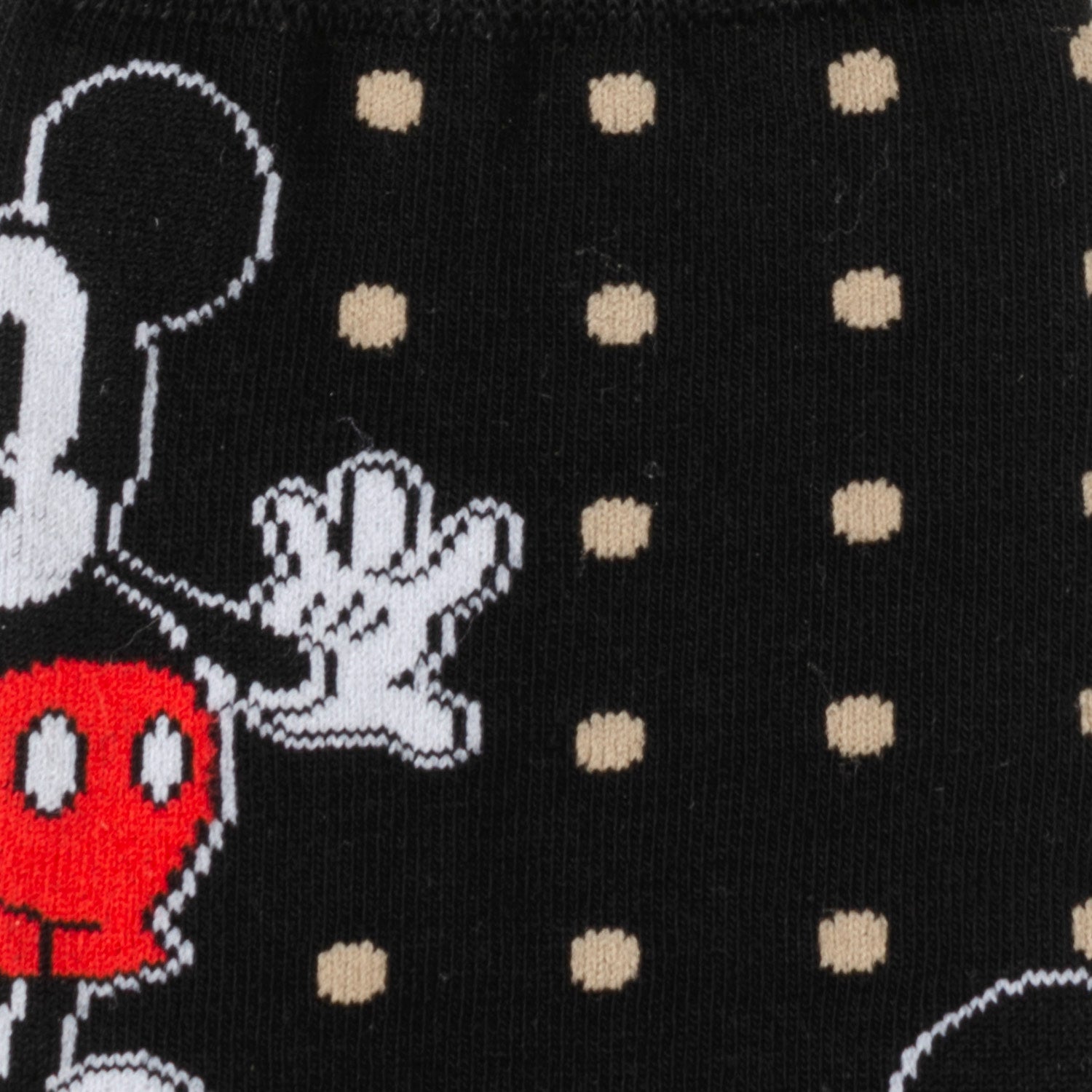 Close-up of a character with a red circle and white gloves on a black background with beige dots.
