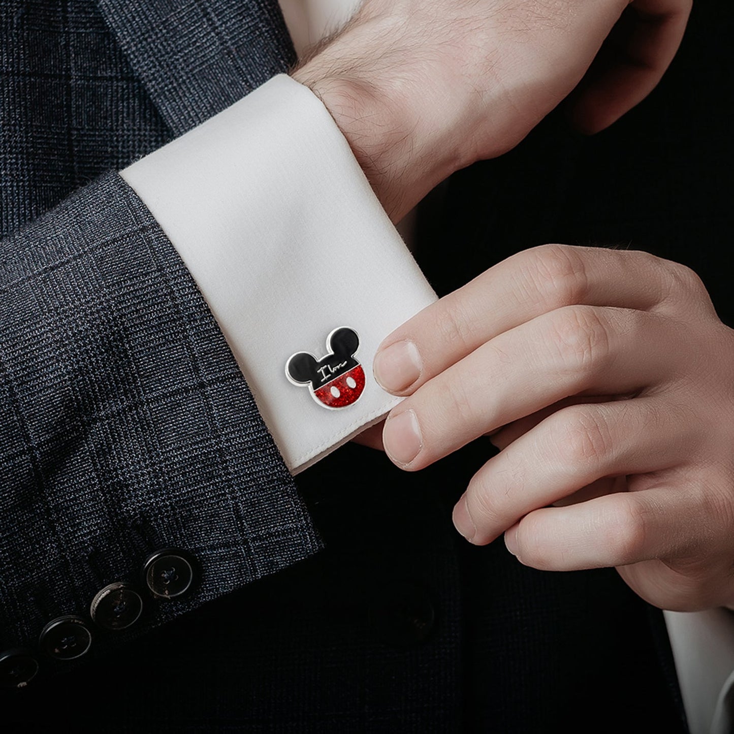 Cufflink with a cartoon character design on a white cuff against a dark suit background