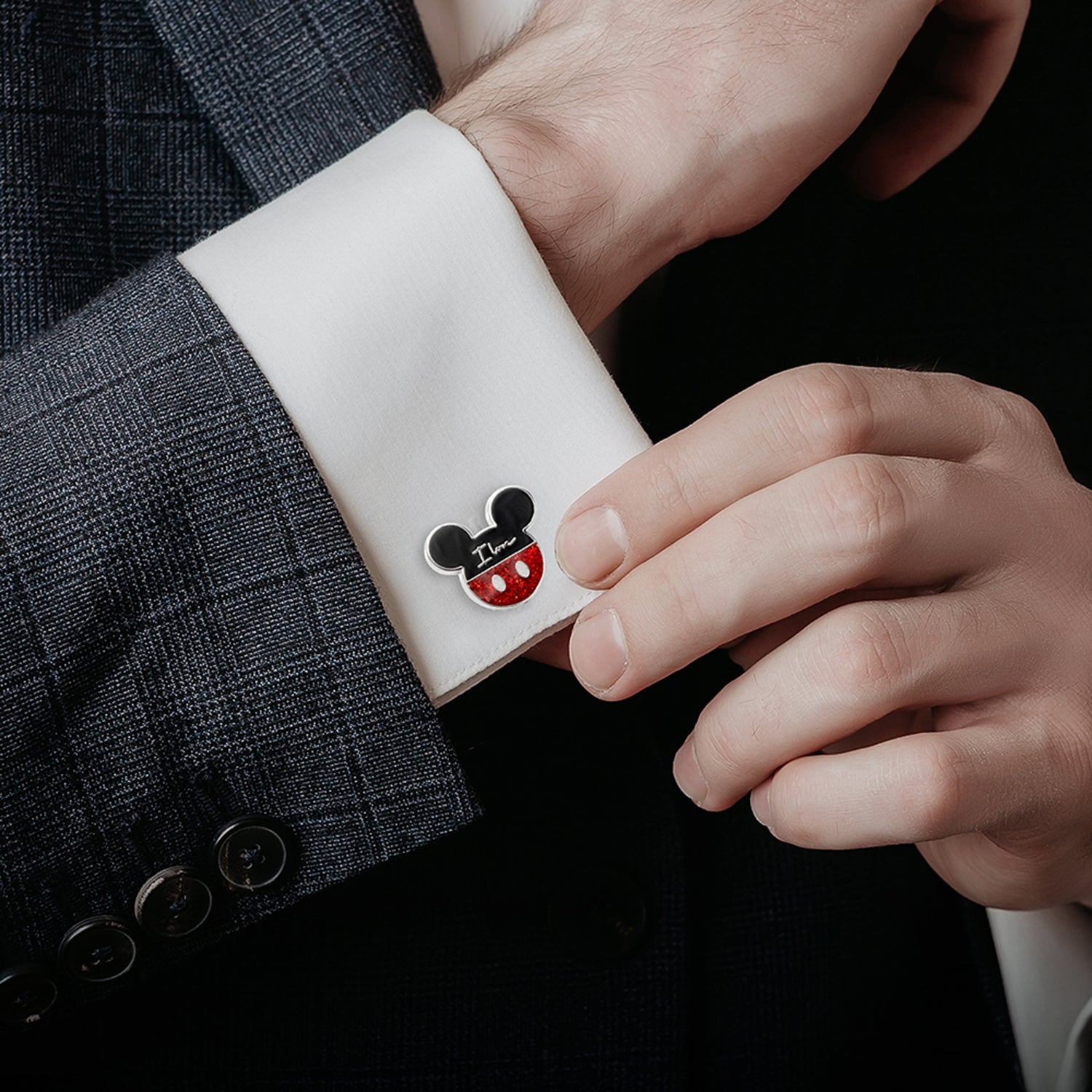 Cufflink with a cartoon character design on a white cuff against a dark suit background