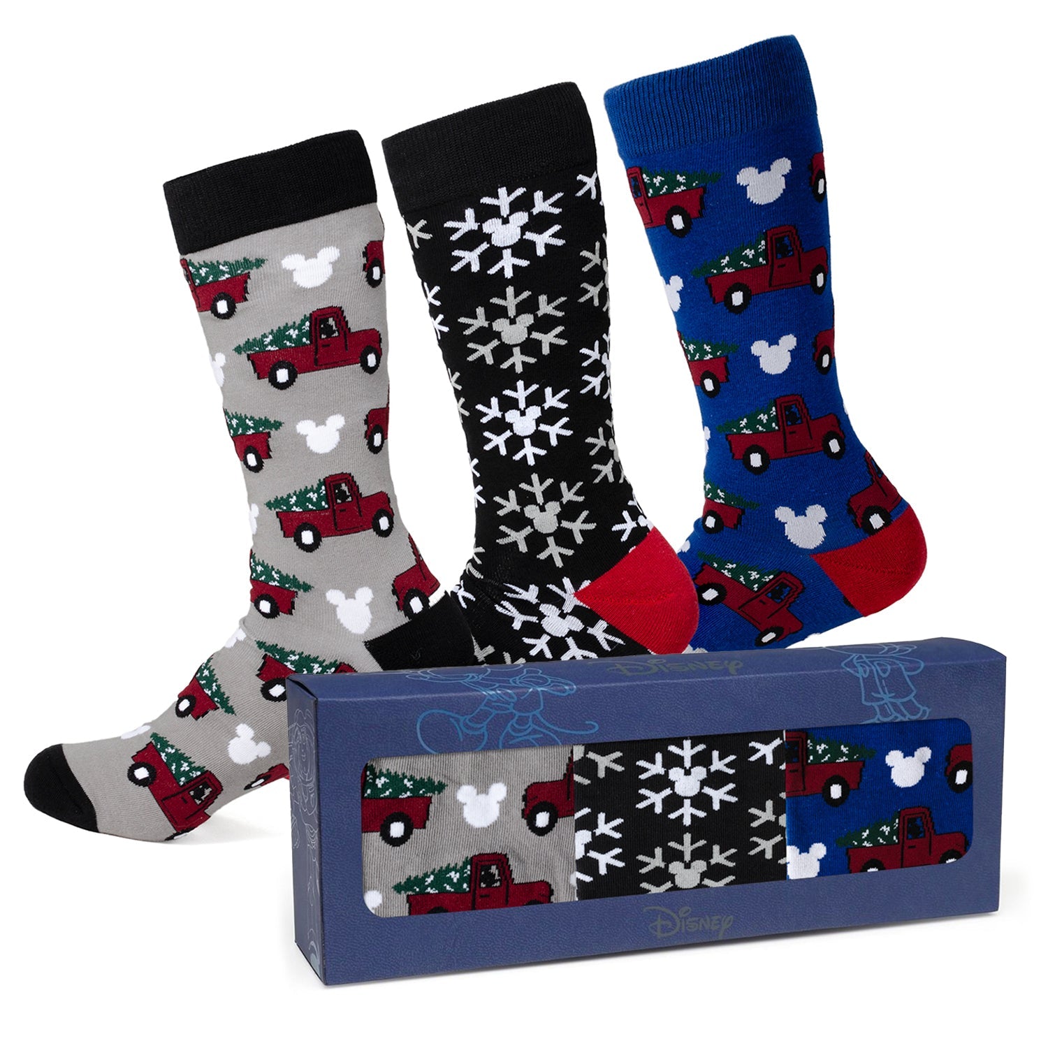 Three pairs of Christmas-themed socks with a box in the foreground on a white background