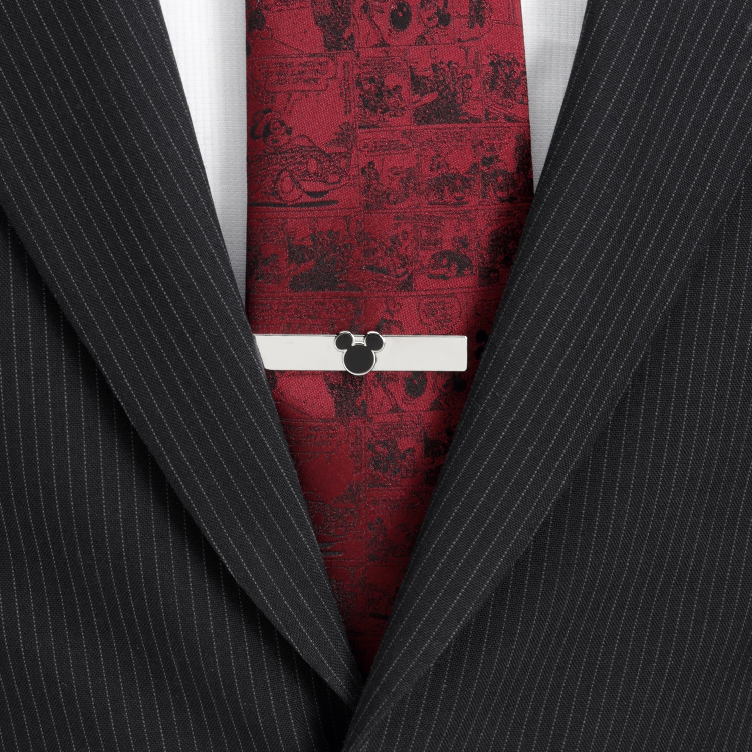 Red tie with black pattern and white bar over a black pinstripe suit