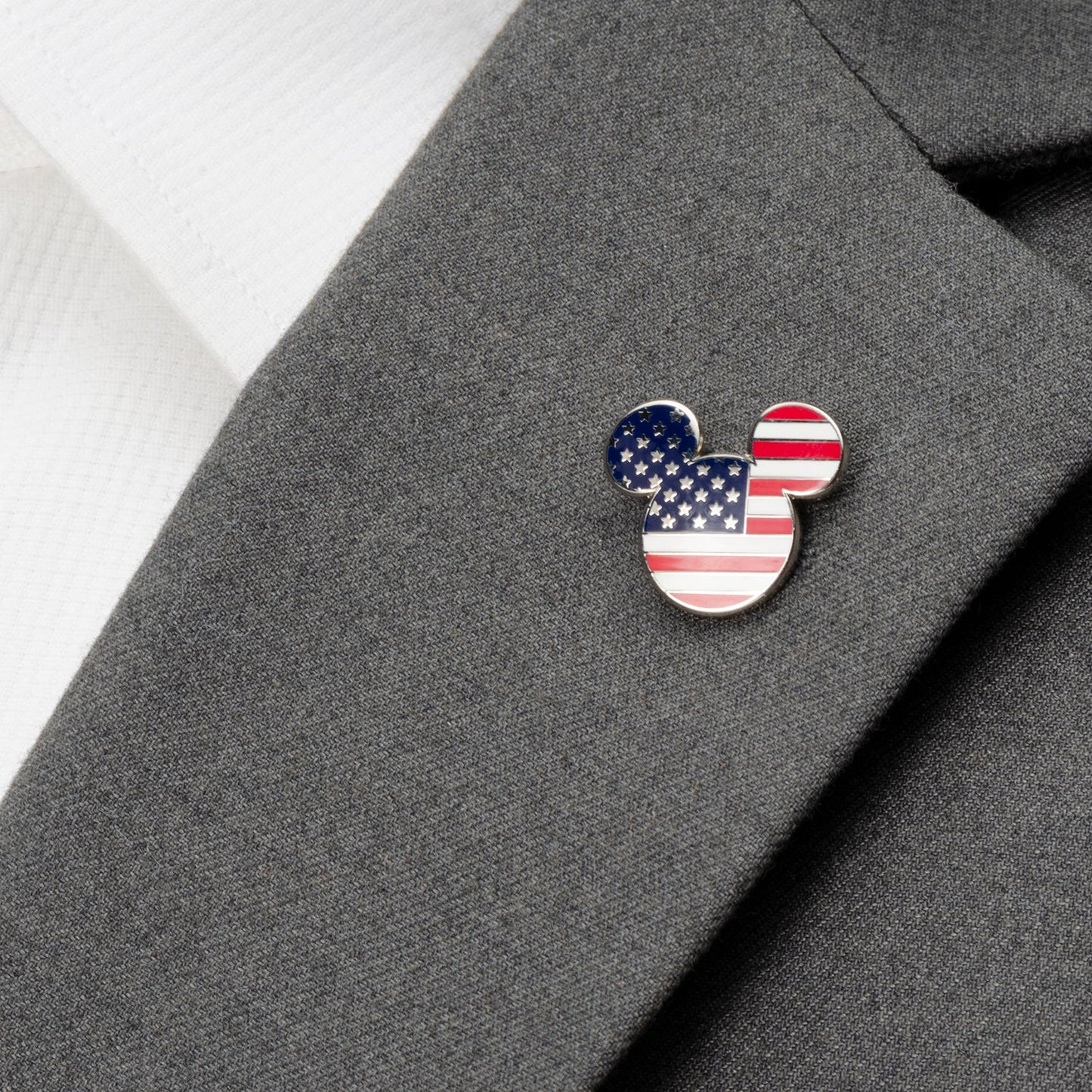 American flag-themed Mickey Mouse ear pin on a gray suit jacket.
