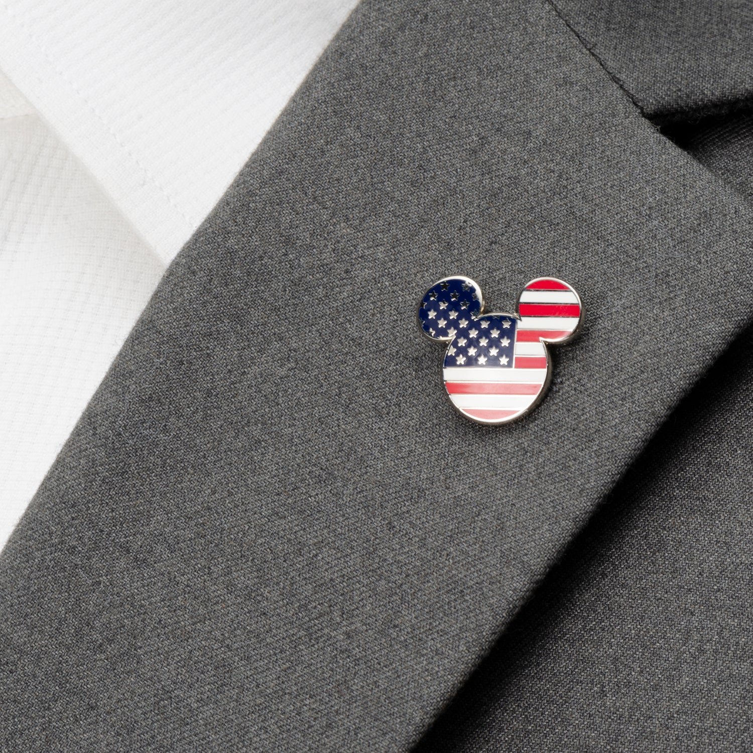 American flag-themed Mickey Mouse ear pin on a gray suit jacket.