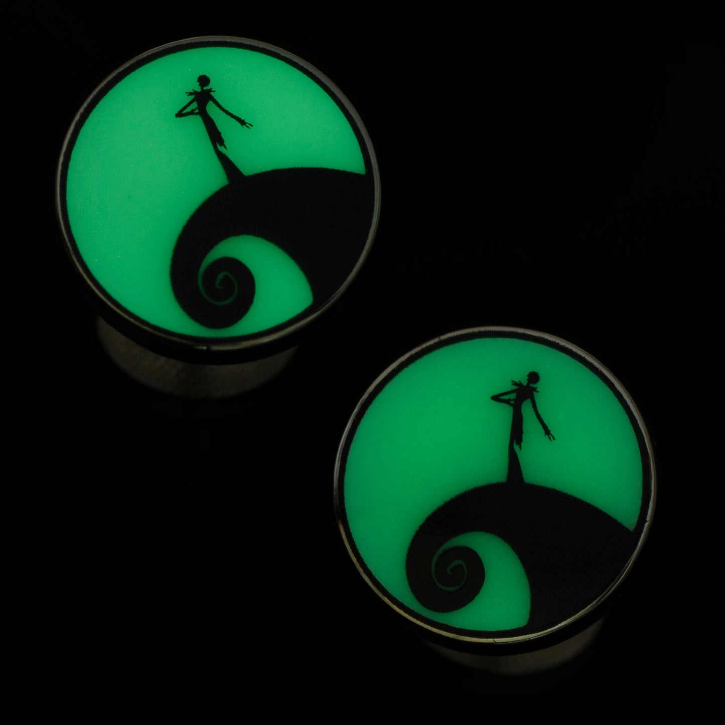 Glowing green plugs with a silhouette design on a black background