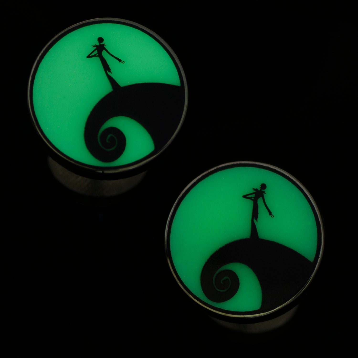 Glowing green plugs with a silhouette design on a black background