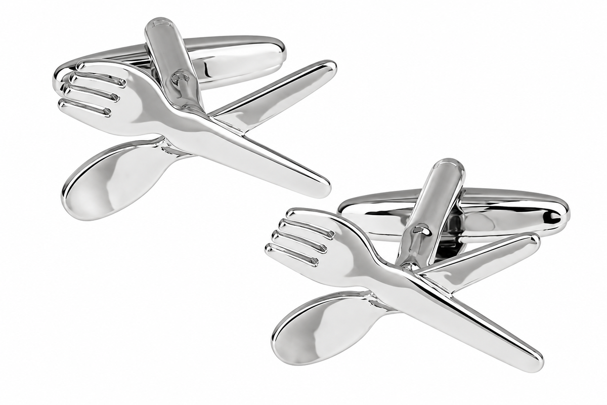A pair of silver-toned cufflinks shaped like crossed cutlery, with one fork and one spoon crossing behind a knife, shown on a plain white background.