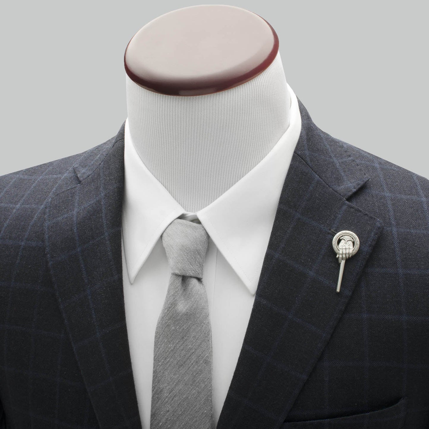 Mannequin wearing a dark gray checkered suit with a white shirt and gray tie, on a light gray background.