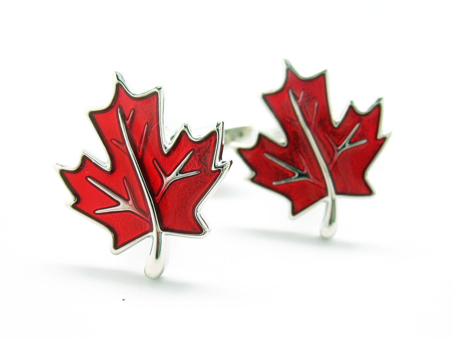 Red maple leaf cufflinks in silver and red enamel displayed on white background.