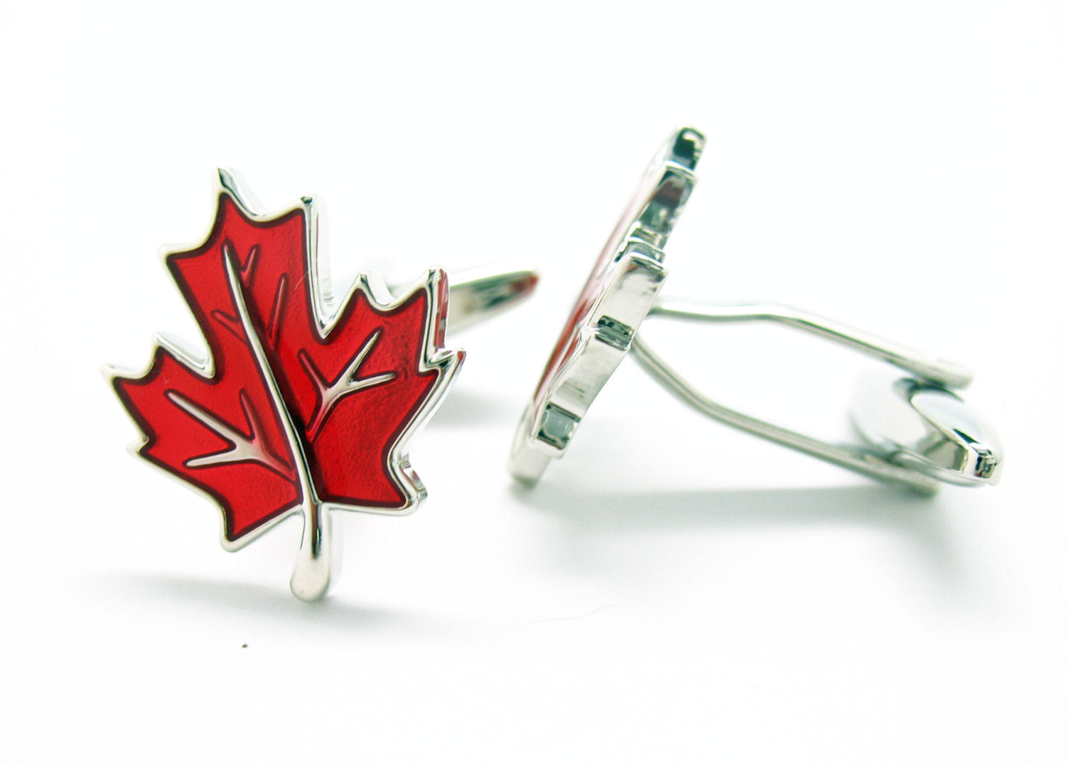 Red maple leaf cufflinks in silver and red enamel displayed on white background.