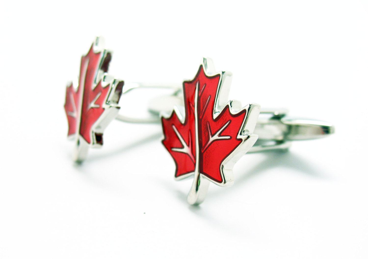Red maple leaf cufflinks in silver and red enamel displayed on white background.
