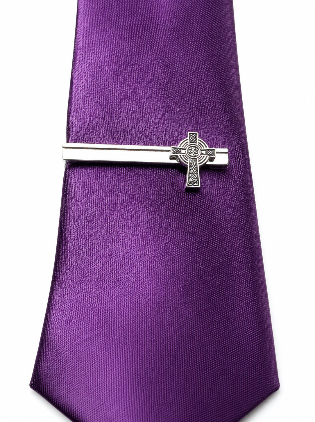 Silver tie clip on a purple tie against a white background
