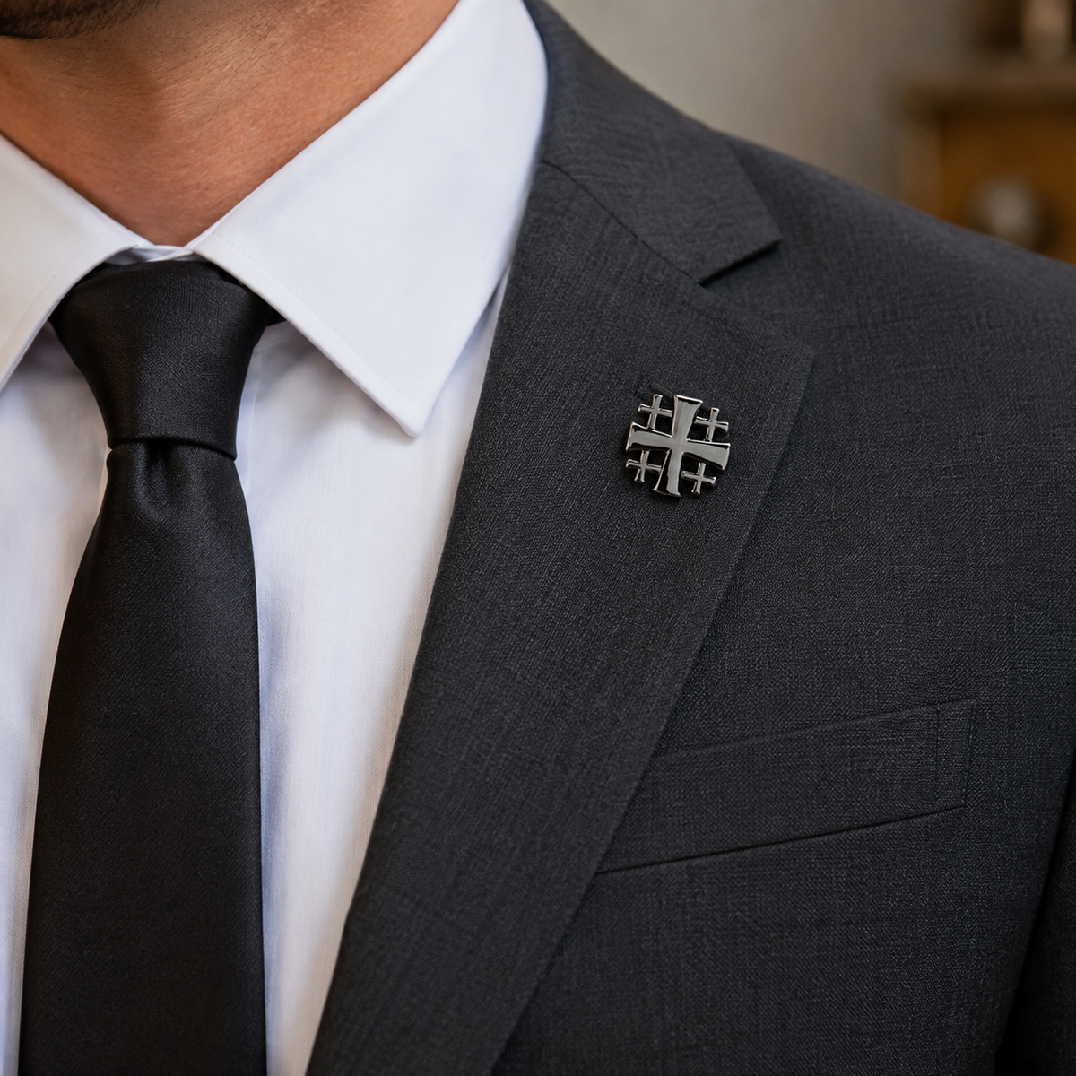 Gunmetal Jerusalem Cross lapel pin worn on charcoal suit