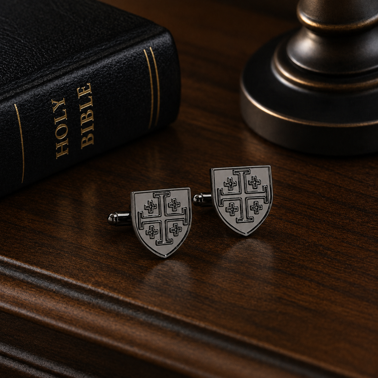 Jerusalem Cross shield cufflinks beside Bible on wooden nightstand