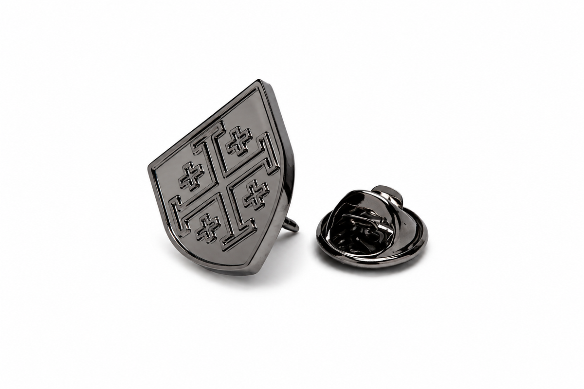 A dark metallic shield-shaped lapel pin with a cross motif, shown alongside its reverse clasp on a clean white background.