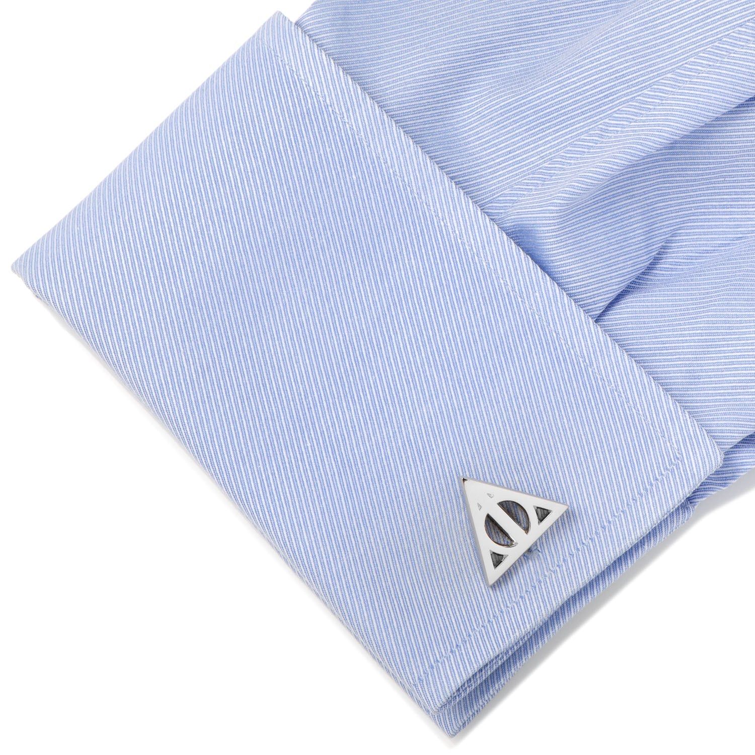 Cufflinks with a triangle design on a light blue striped shirt.