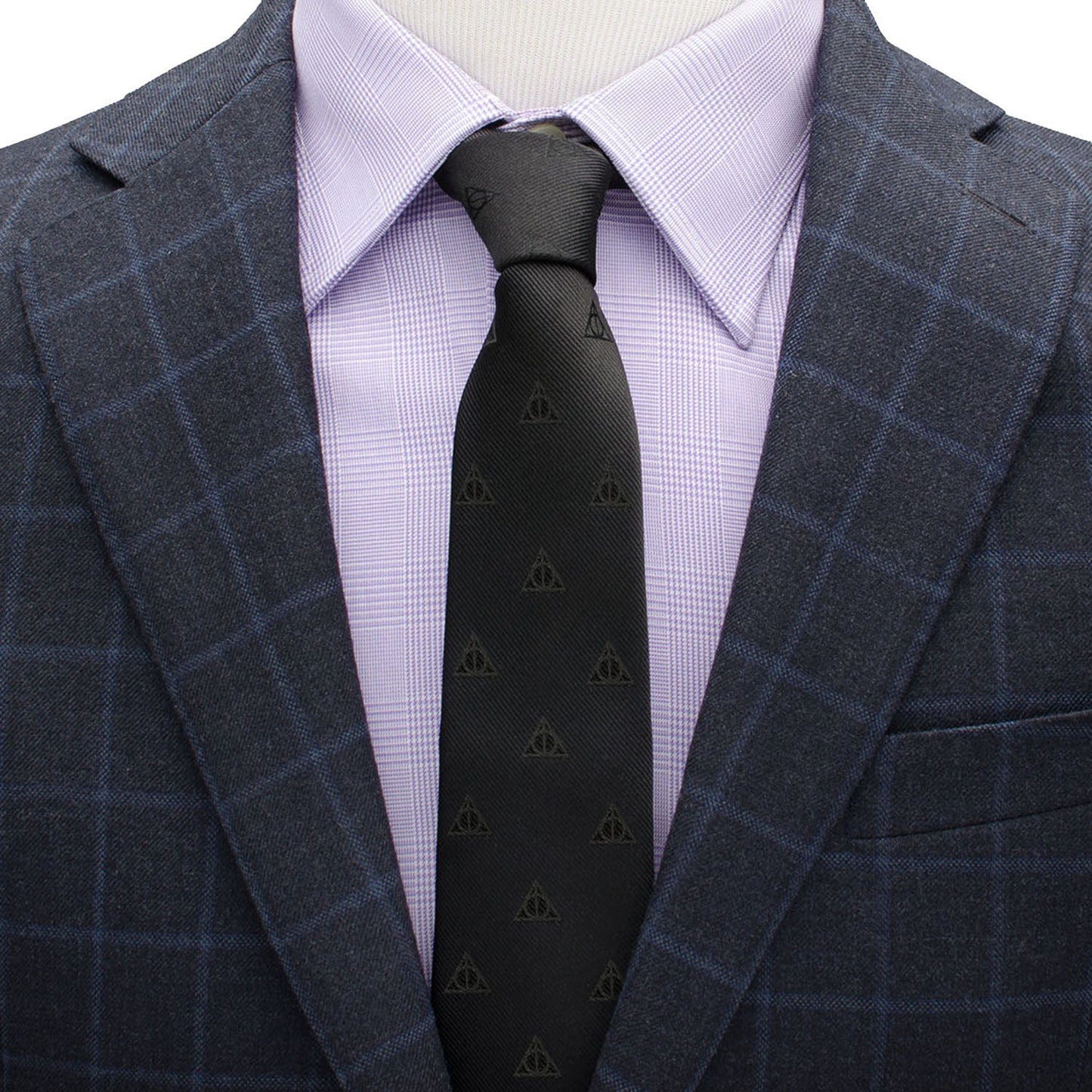 Gray checkered suit jacket over a light purple dress shirt with a black tie featuring triangle patterns.