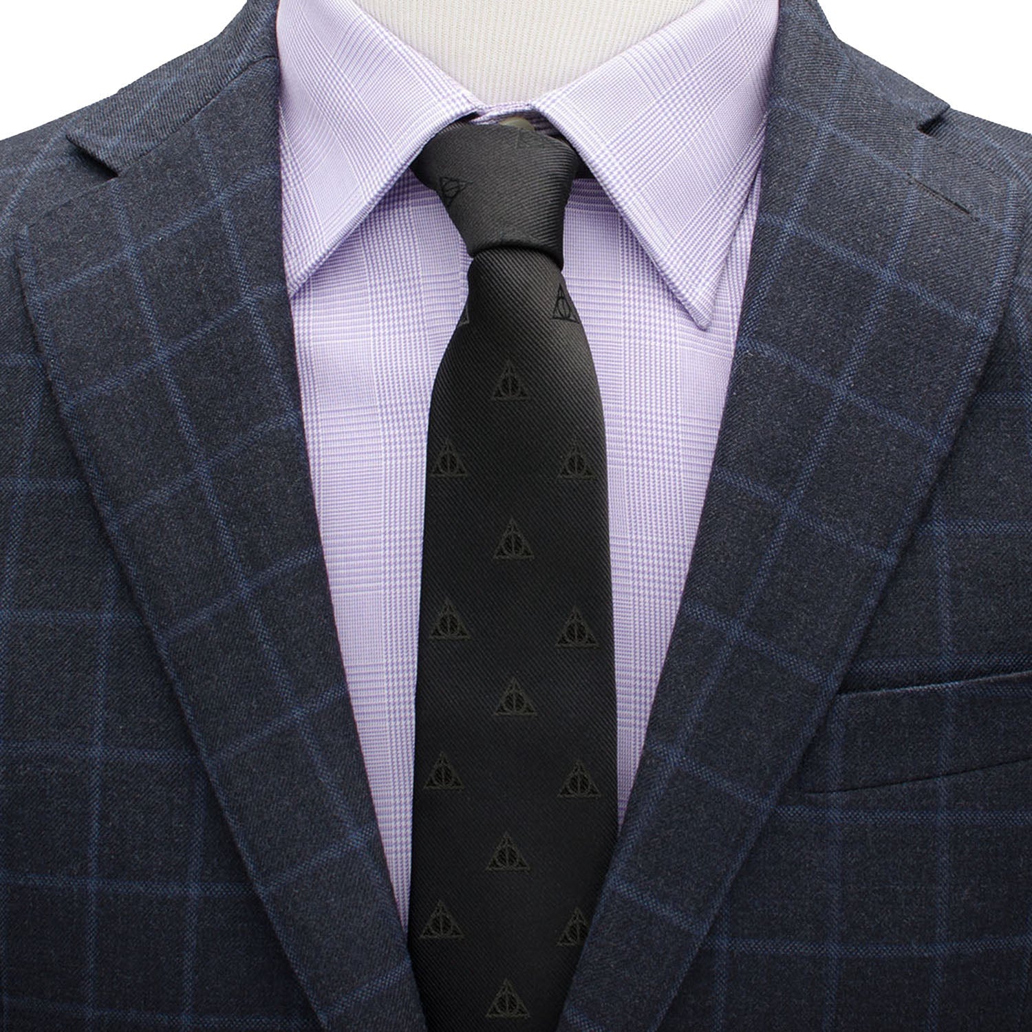 Gray checkered suit jacket over a light purple dress shirt with a black tie featuring triangle patterns.