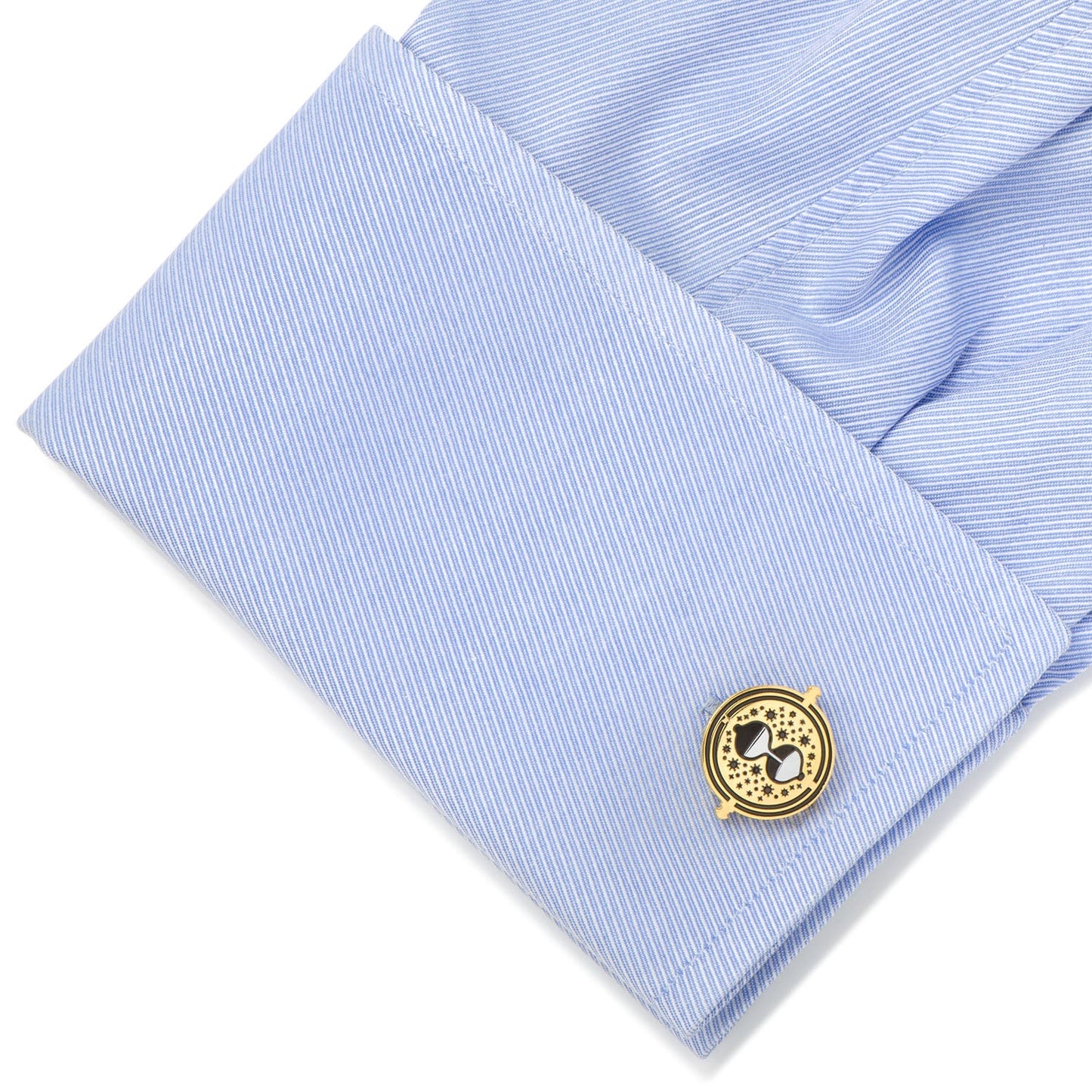 Gold cufflink on a light blue dress shirt with a white background