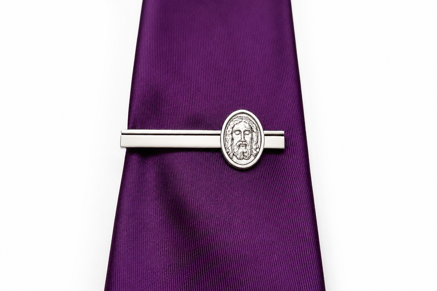 Silver tie clip on a purple tie against a white background