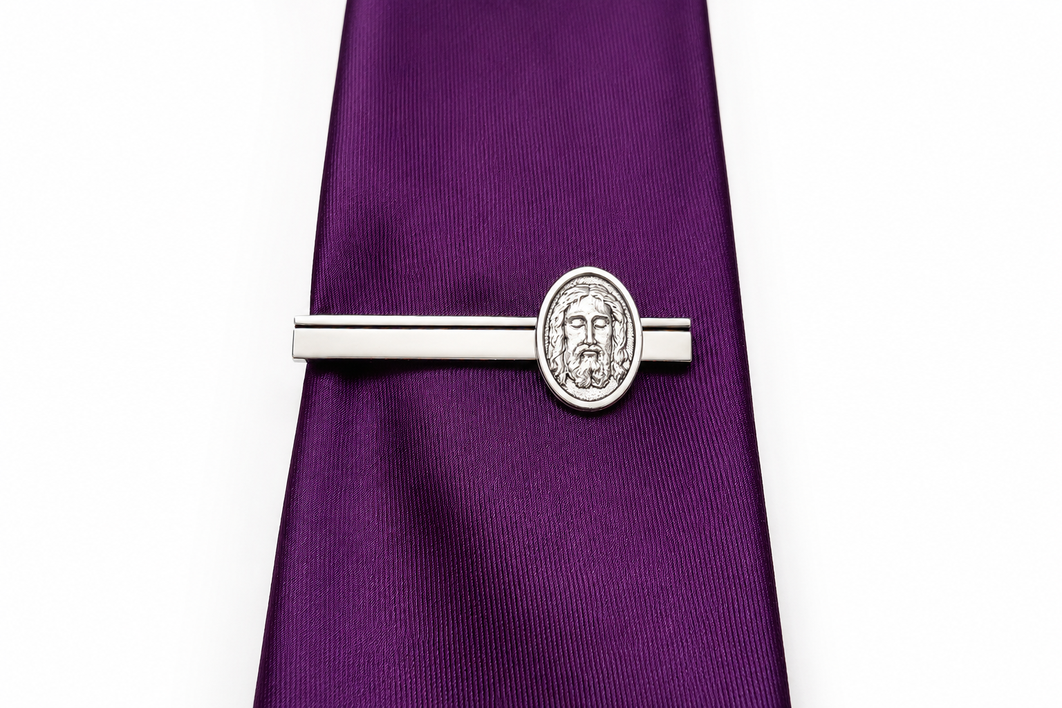 Silver tie clip on a purple tie against a white background