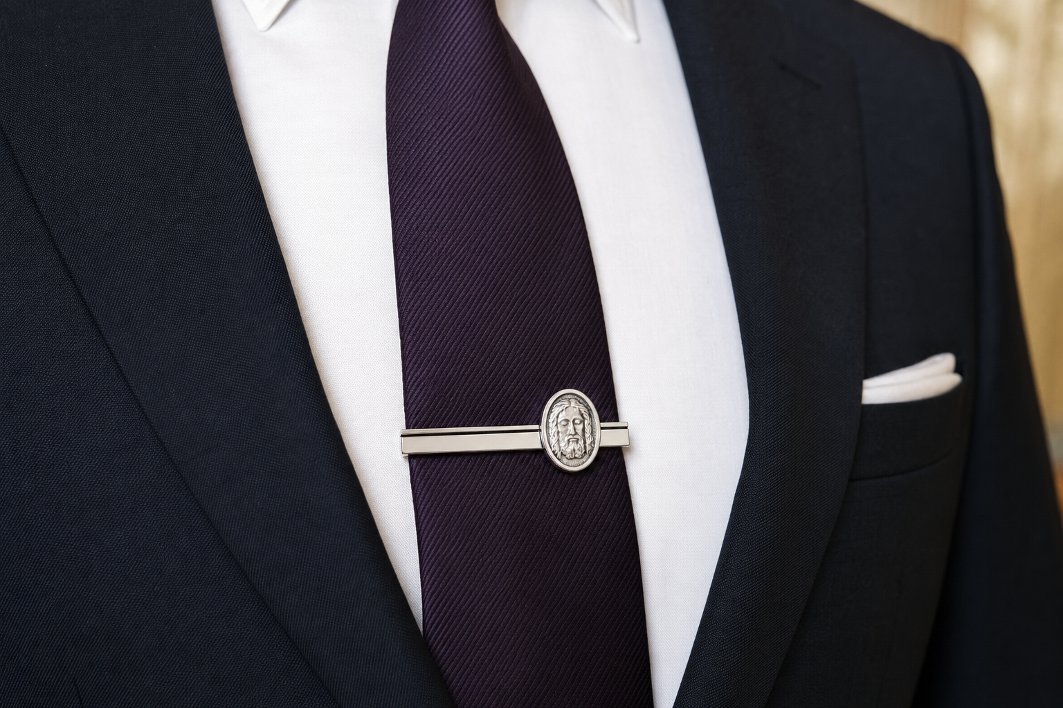 Black suit with a purple tie and silver tie clip on a white shirt.