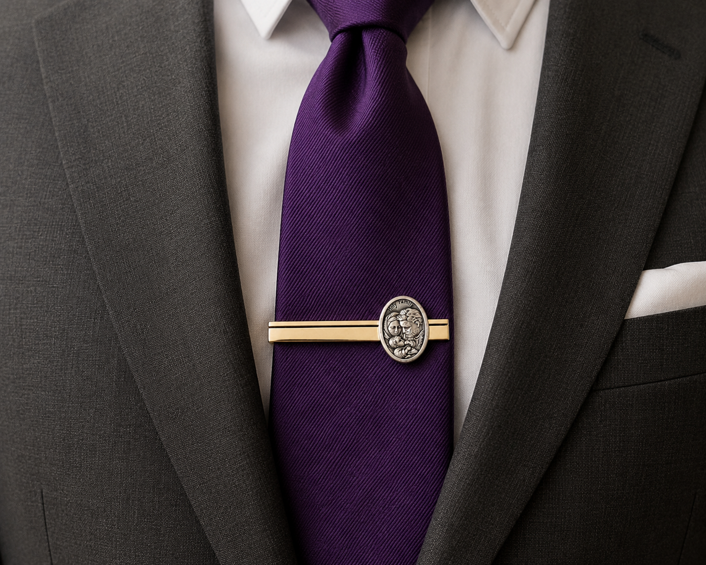A close-up of a purple silk necktie with a gold and silver tie bar, worn with a white dress shirt and dark gray suit jacket.