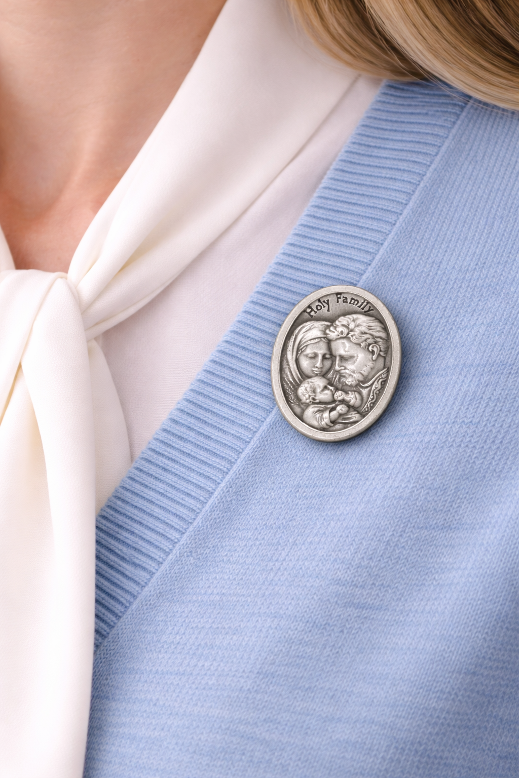 Silver brooch with a design on a light blue cardigan