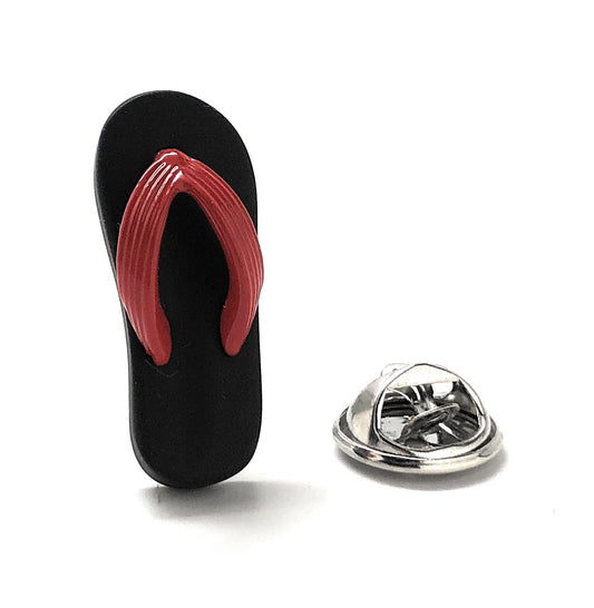 Black flip-flop with red sole and a silver metal badge on a white background