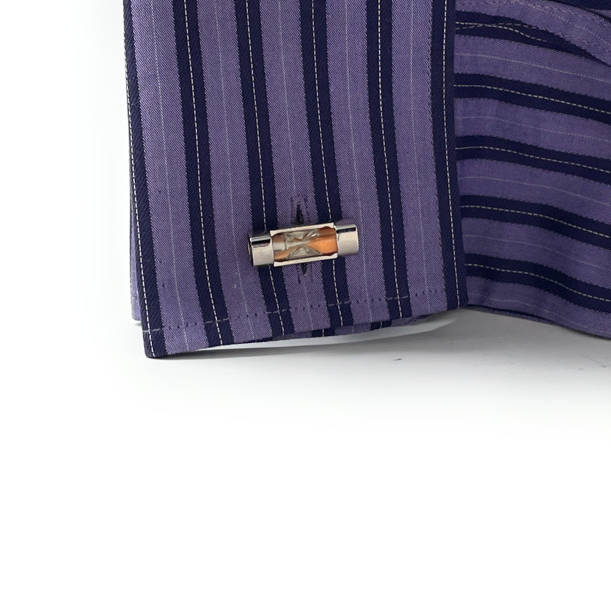 Close-up of a purple striped shirt with a cufflink on a white background