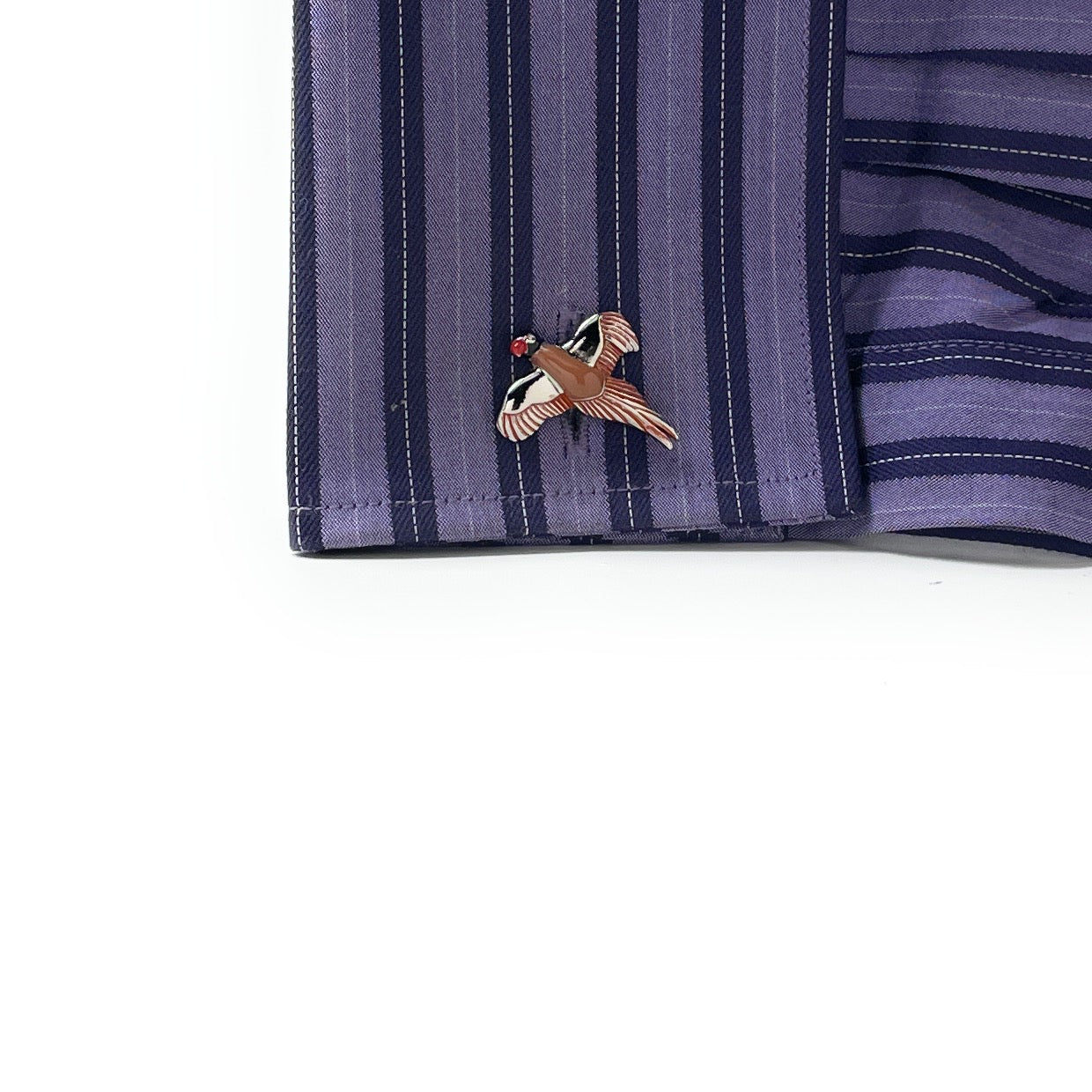 Close-up of a striped fabric with a bird-shaped brooch on a white background