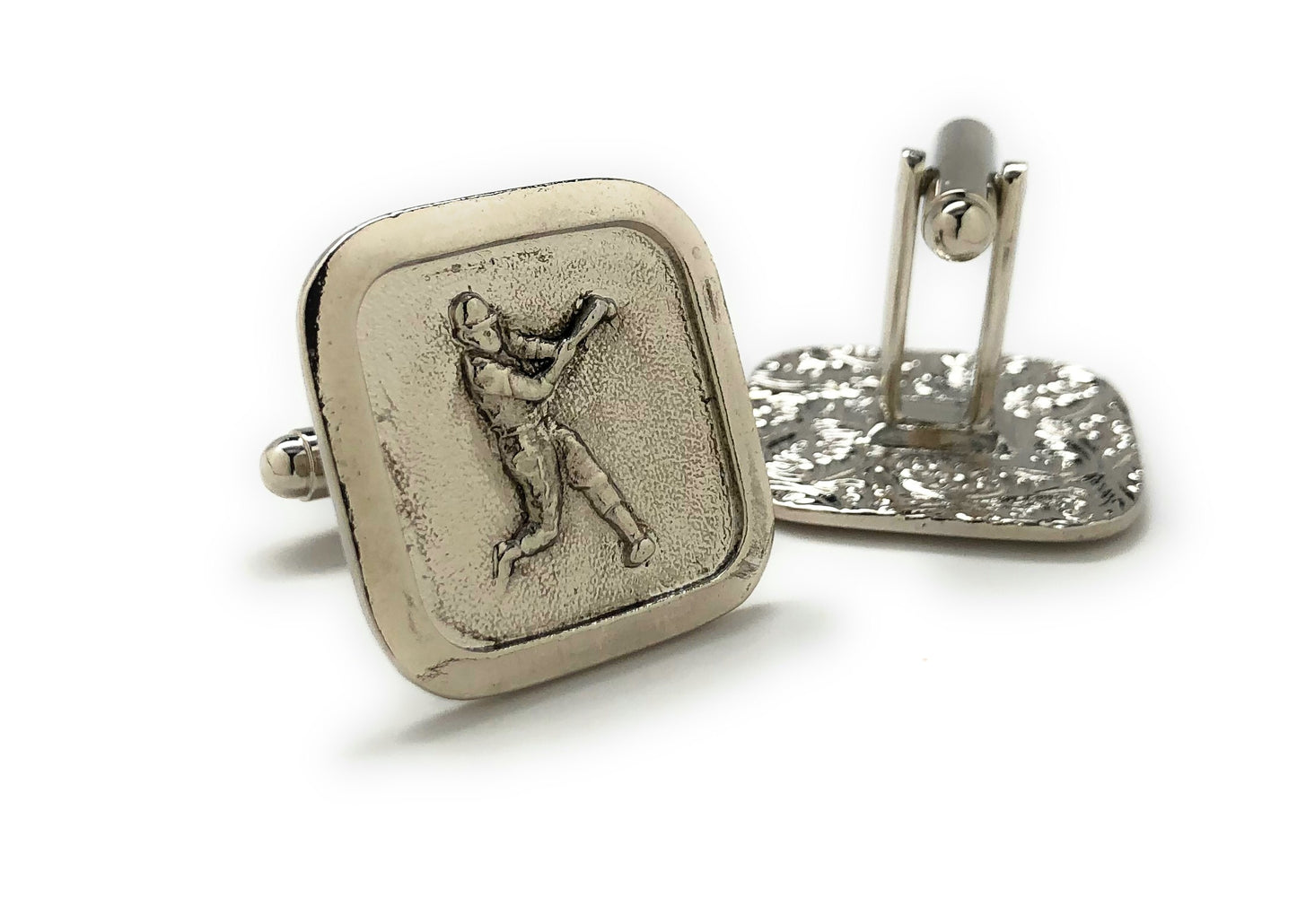 Silver cufflinks with a engraved design on a white background