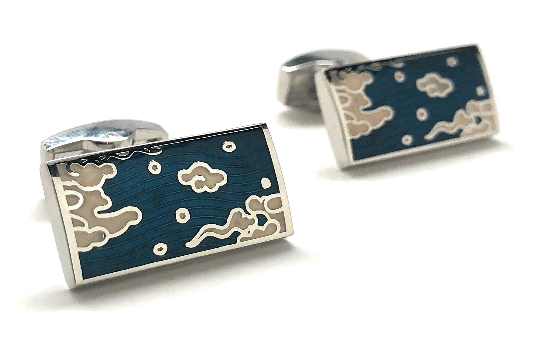 Cufflinks with a design of a man and woman holding hands against a night sky with stars and clouds on a white background.