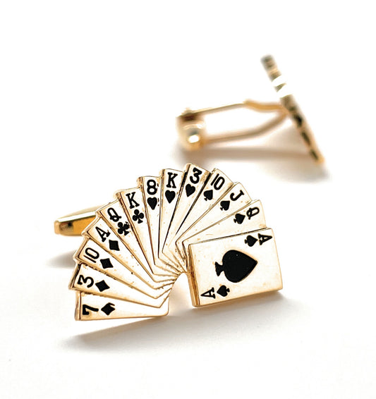 Gold cufflinks with playing card suits on a white background