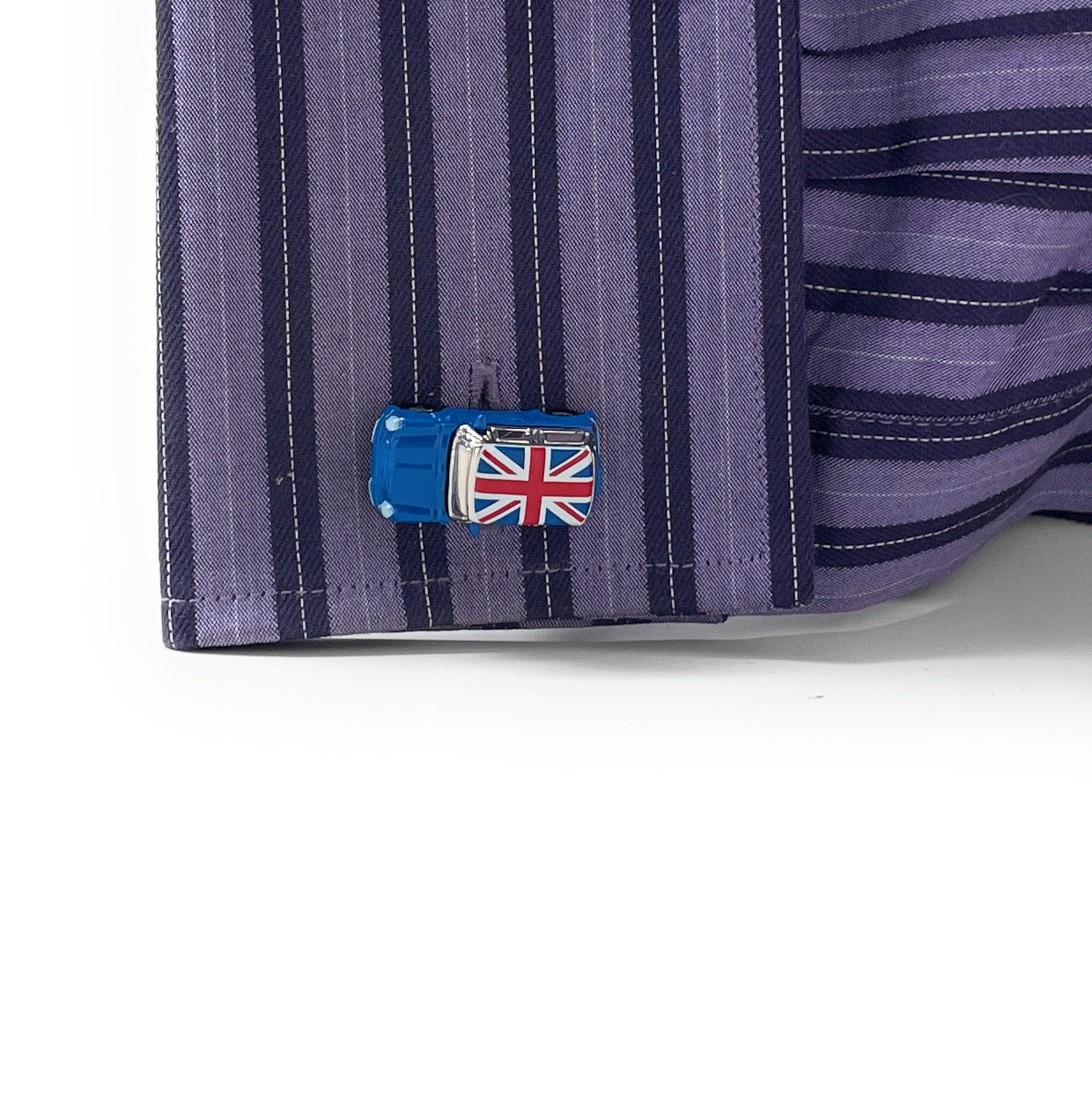 Close-up of a shirt cuff with a blue cufflink featuring a Union Jack design on a white background.