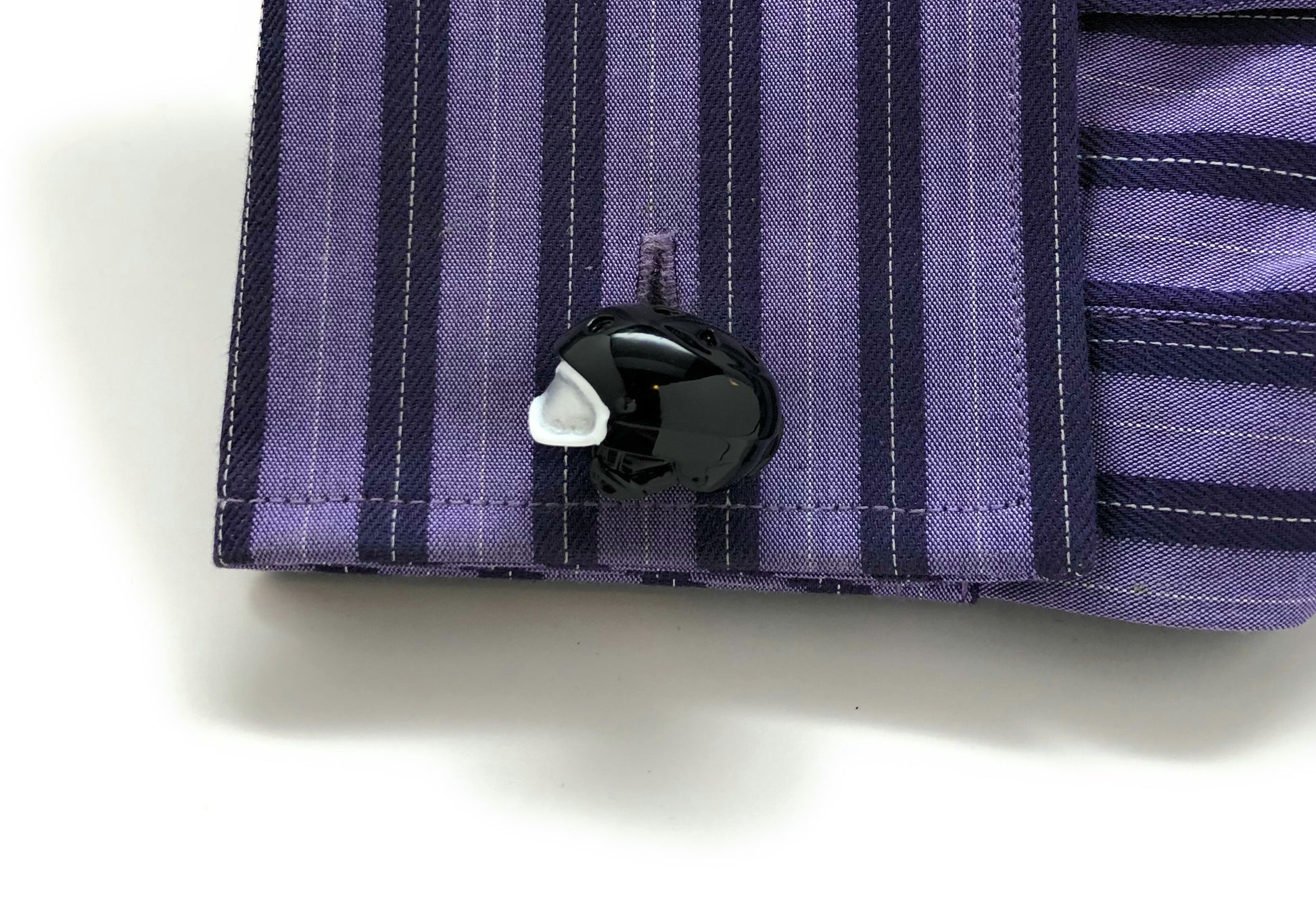Close-up of a purple striped shirt with a button on a white background