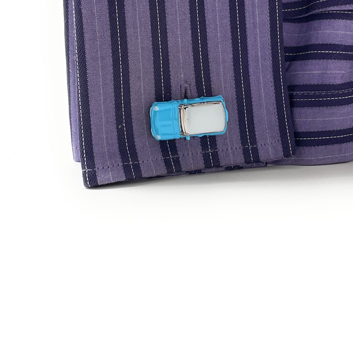 Close-up of a shirt with a blue car-shaped cufflink on a white background