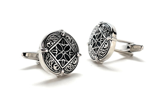Pair of silver cufflinks with intricate designs on a white background