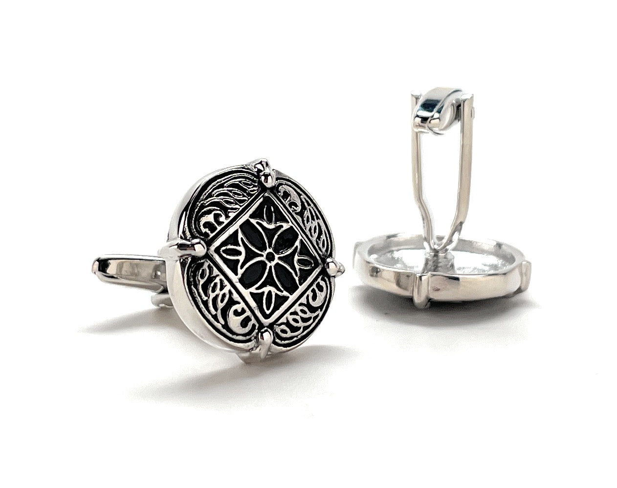 Silver cufflinks with intricate design on a white background