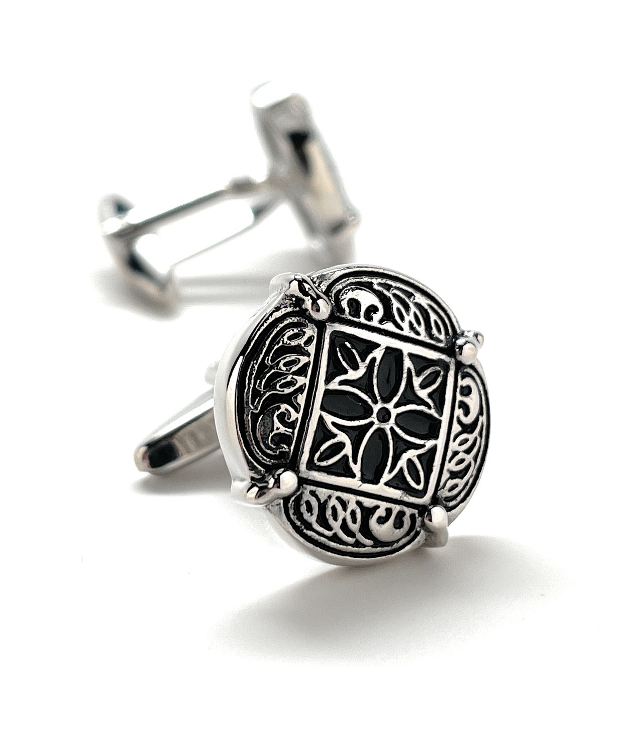 Silver cufflinks with intricate black design on a white background