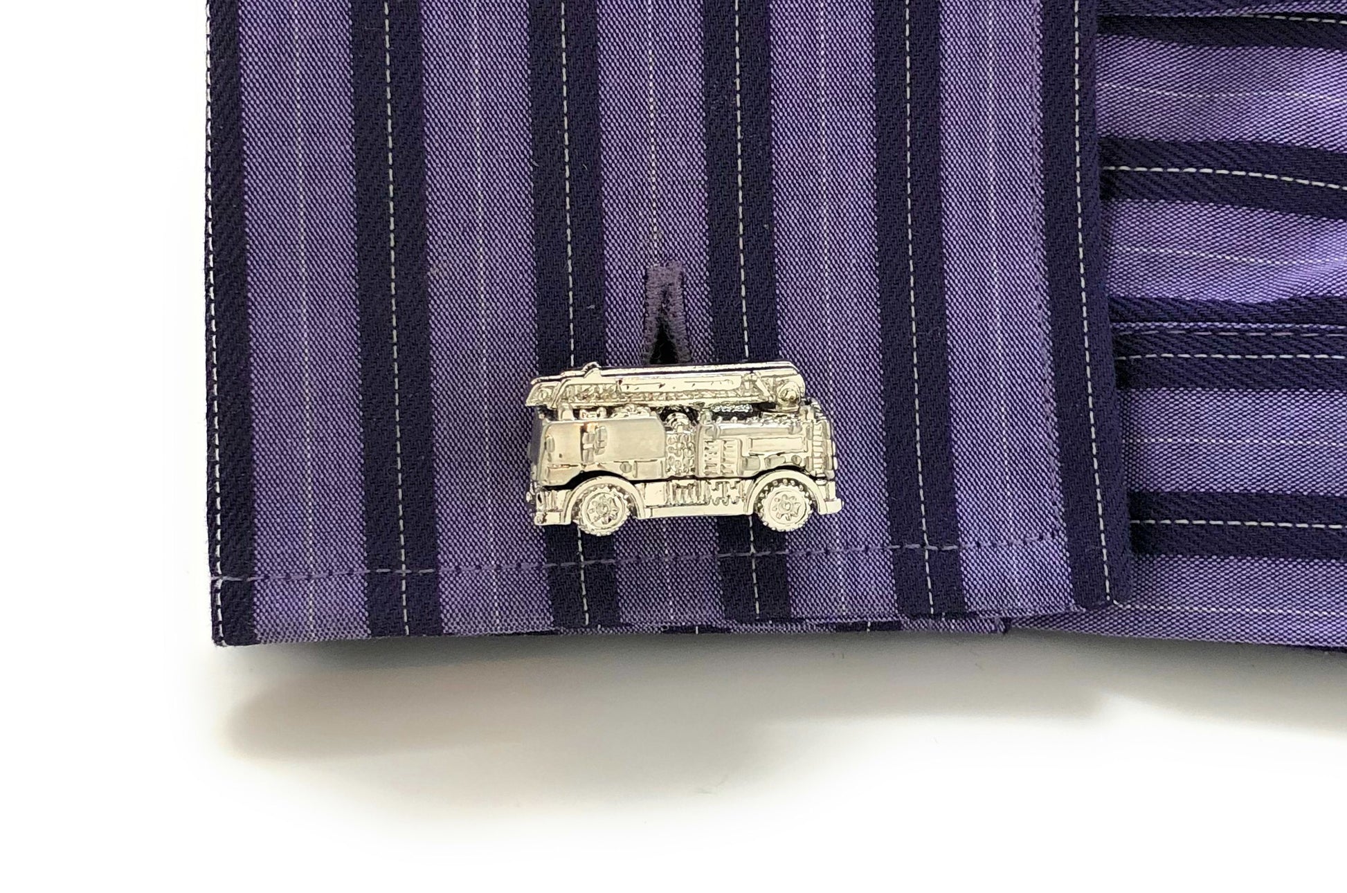 Silver truck-shaped lapel pin on a purple striped shirt