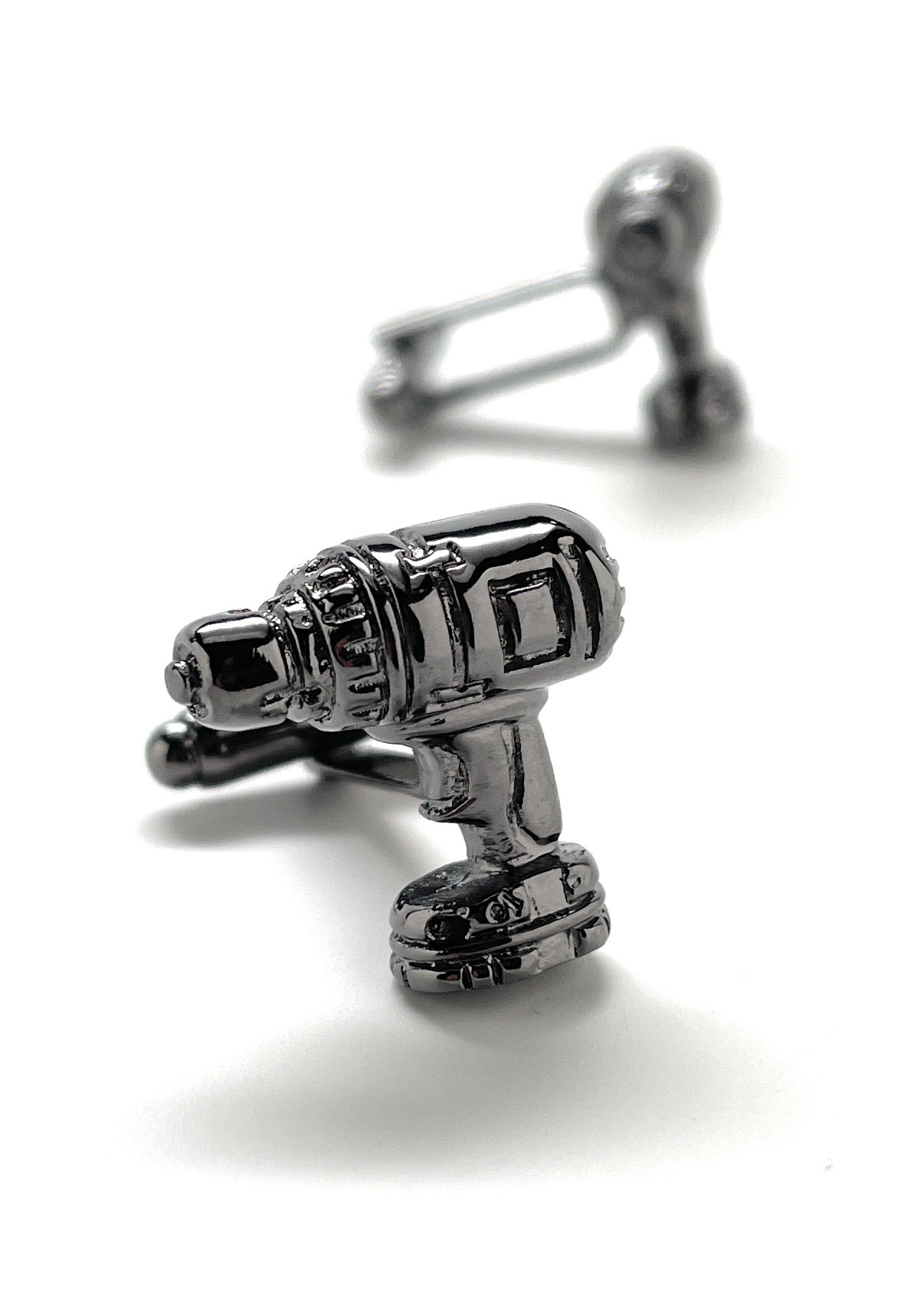Silver cufflinks shaped like a drill on a white background