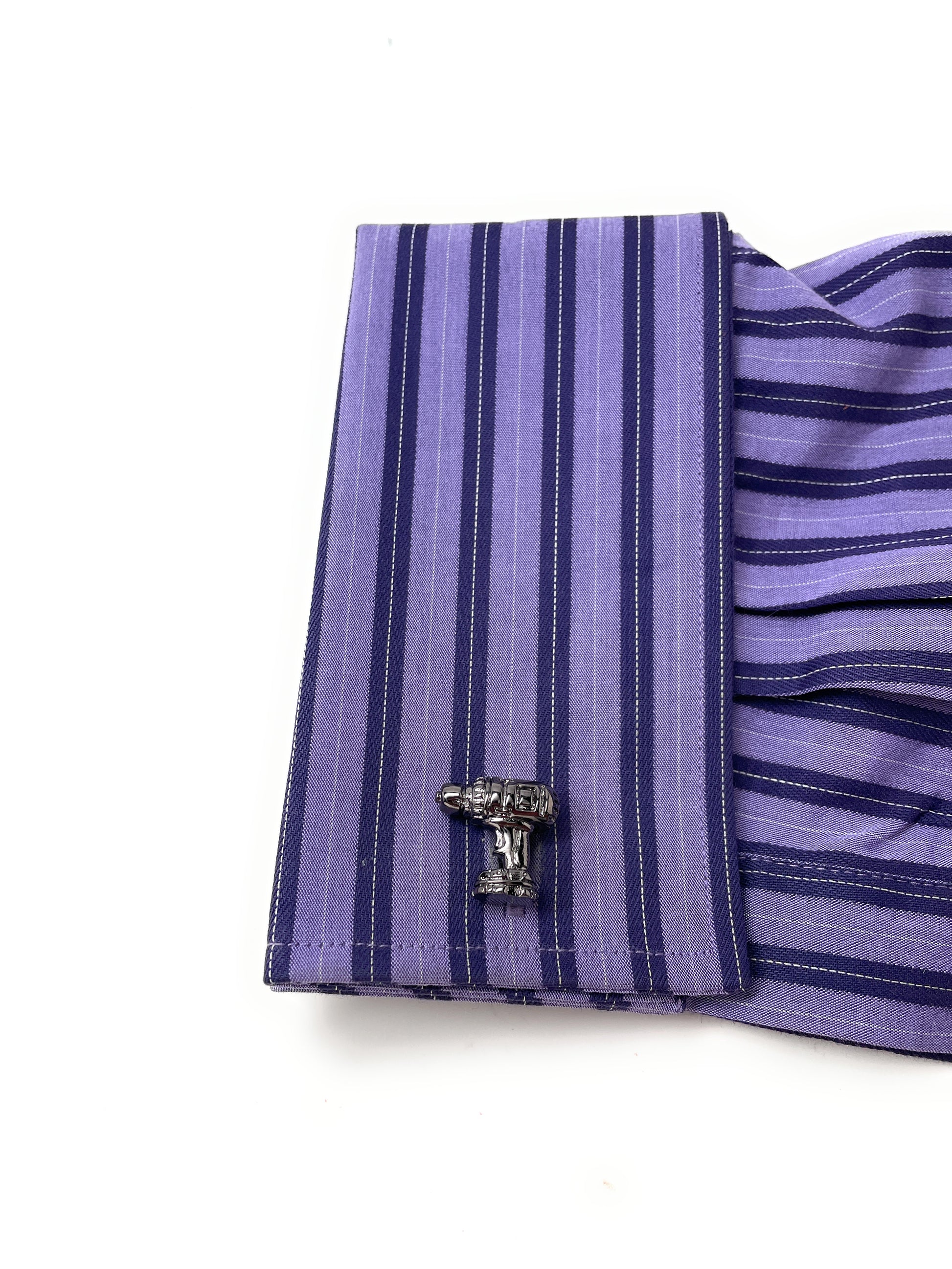 Close-up of a purple and blue striped shirt cuff with a cufflink on a white background